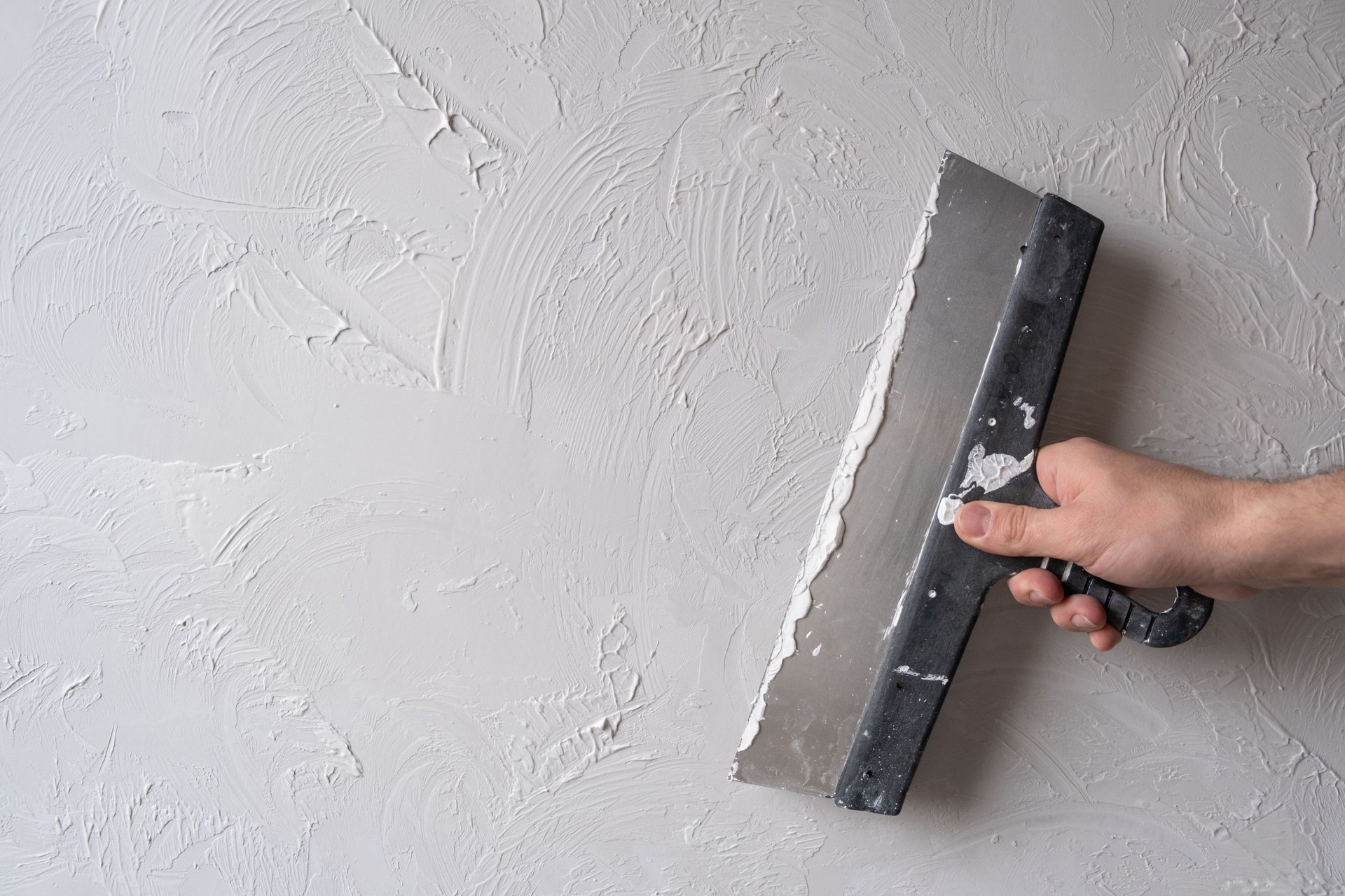 Applying decorative putty. White abstract texture of surface covered with putty